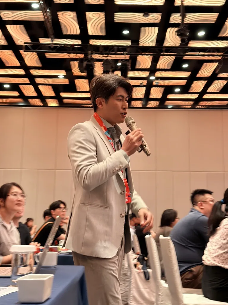 張益豪醫師走下講台，拿著麥克風在來日方腸 2026 研討會聽眾席間分享