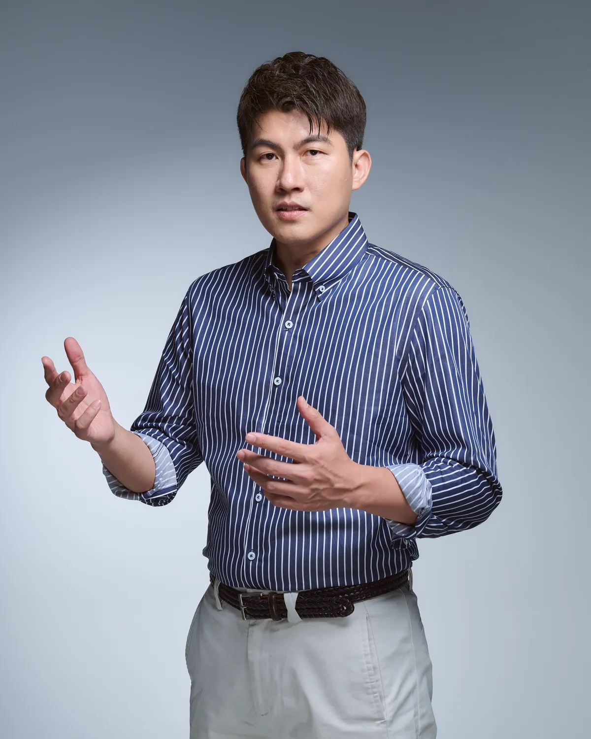 張益豪醫師身穿藍色條紋襯衫，雙手張開正在講解說明，神情投入