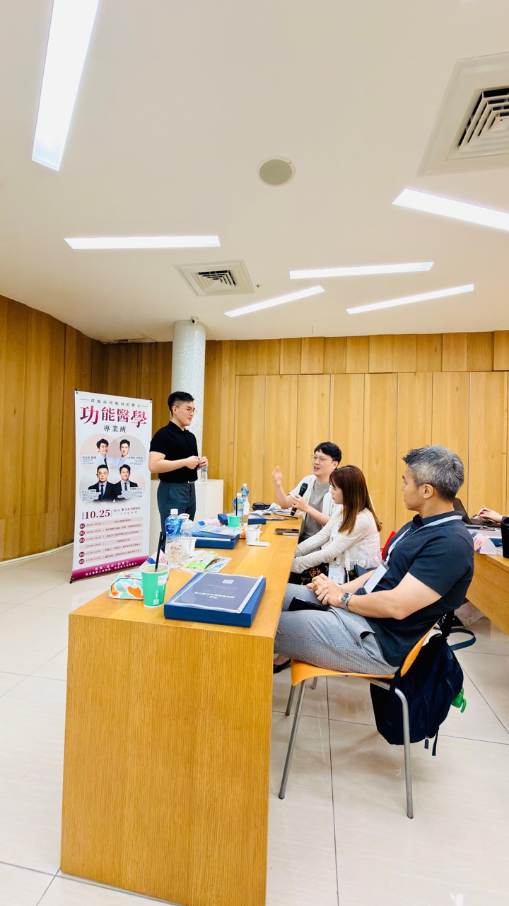 課堂座位間的交流，一位參與者手持麥克風發言，周圍夥伴聆聽。