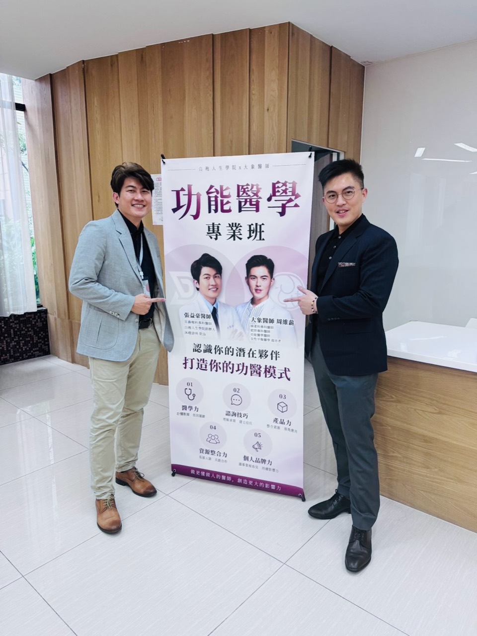 張益豪醫師與大象醫師周維薪站在功能醫學專業班海報兩側合影。