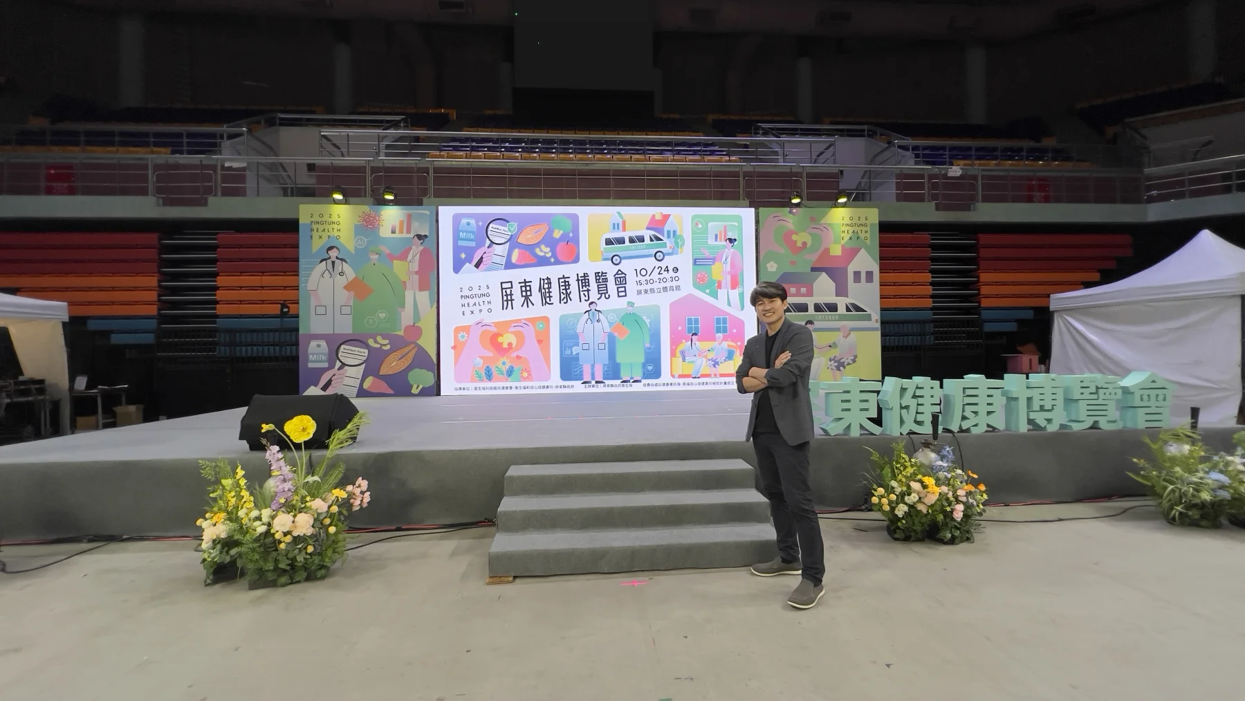 張益豪醫師站在2025屏東健康博覽會主舞台前，舞台背板清楚顯示屏東健康博覽會名稱