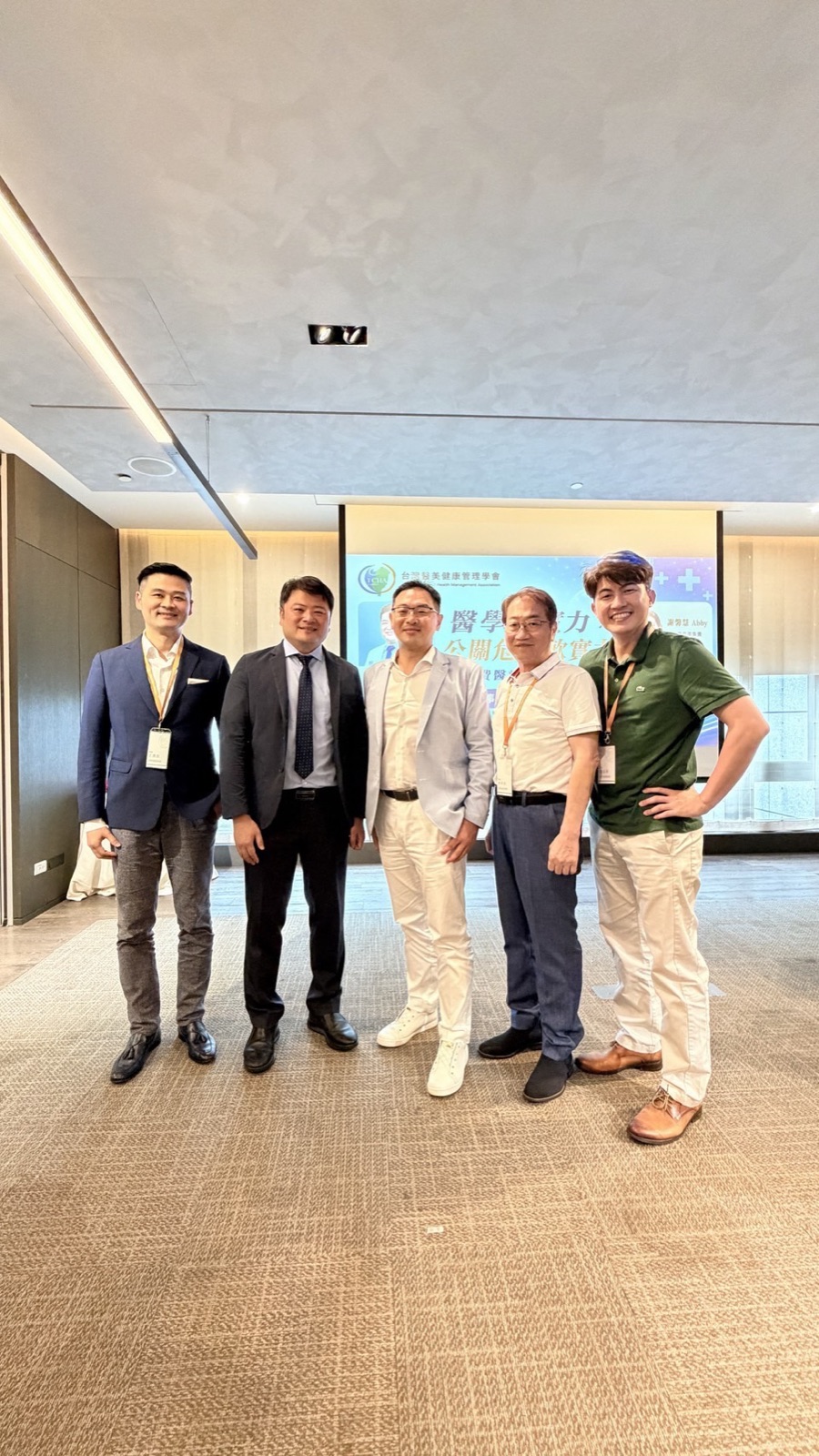 研討會講者與貴賓五人於舞台背板前合影，左二為主講血液淨化與精準預防醫學的王舒民醫師，最右為張益豪醫師