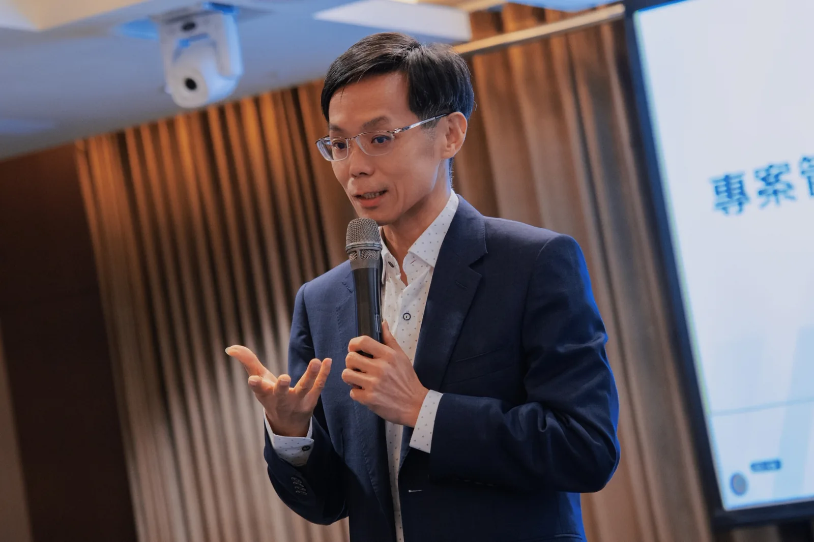 彭建文老師在課堂上手持麥克風授課的特寫
