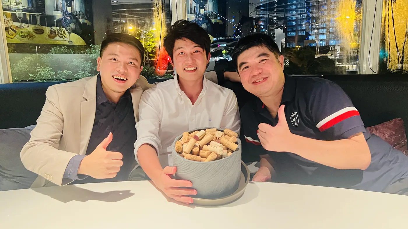 三位與會者圍著一盆軟木塞比讚合影