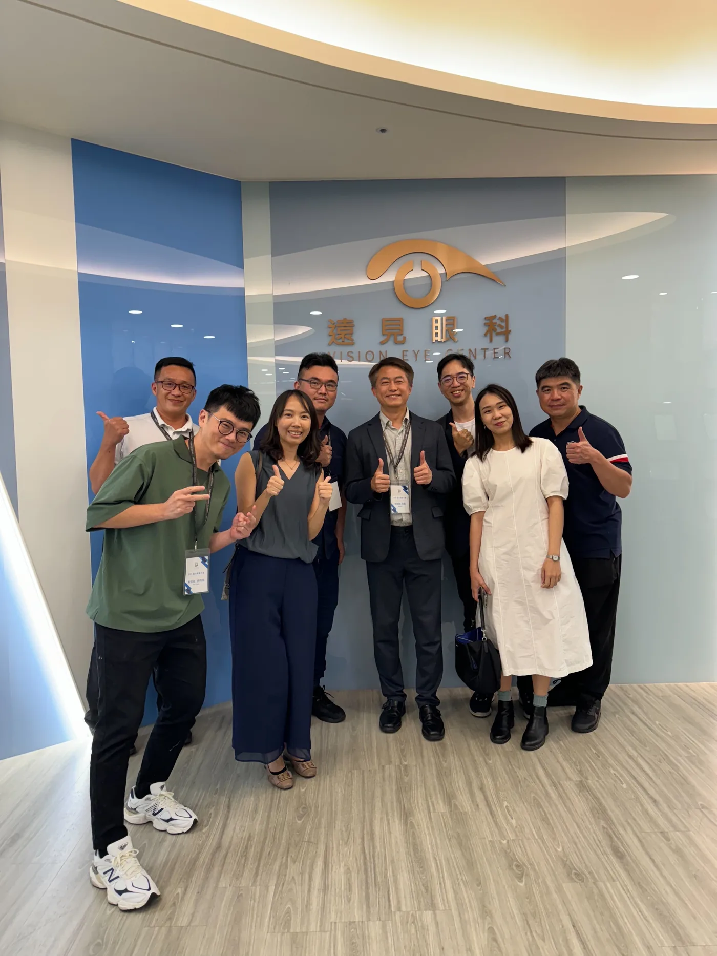 六位與會者在遠見眼科招牌前合影比讚
