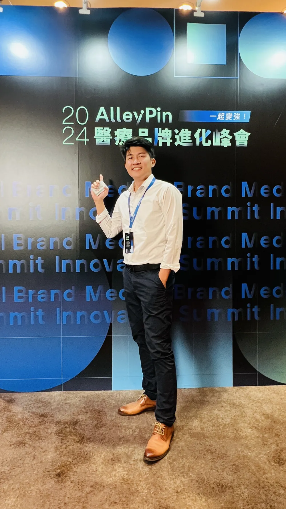 張益豪醫師掛著藍色識別證，單人站在「2024 AlleyPin 醫療品牌進化峰會」直式主視覺背板前擺出姿勢