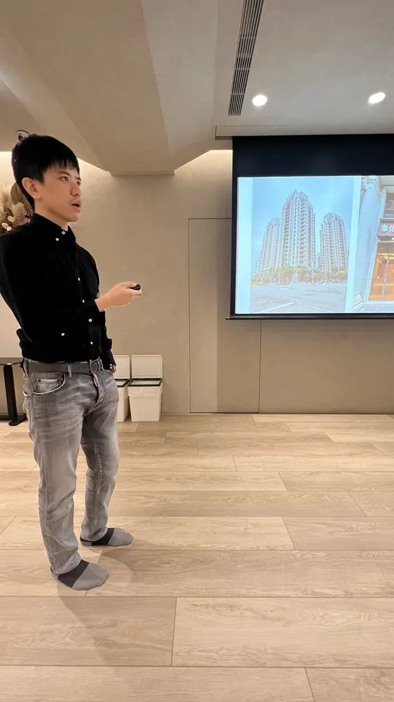 廖醫師站在手繪風城市建築插圖投影片旁分享