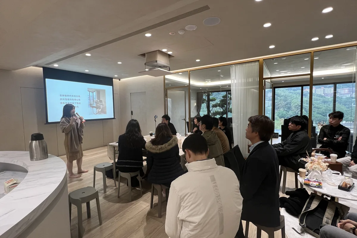 孫克嘉醫師站在原蘊診所吧台旁手持麥克風分享，與會院長圍坐聽講