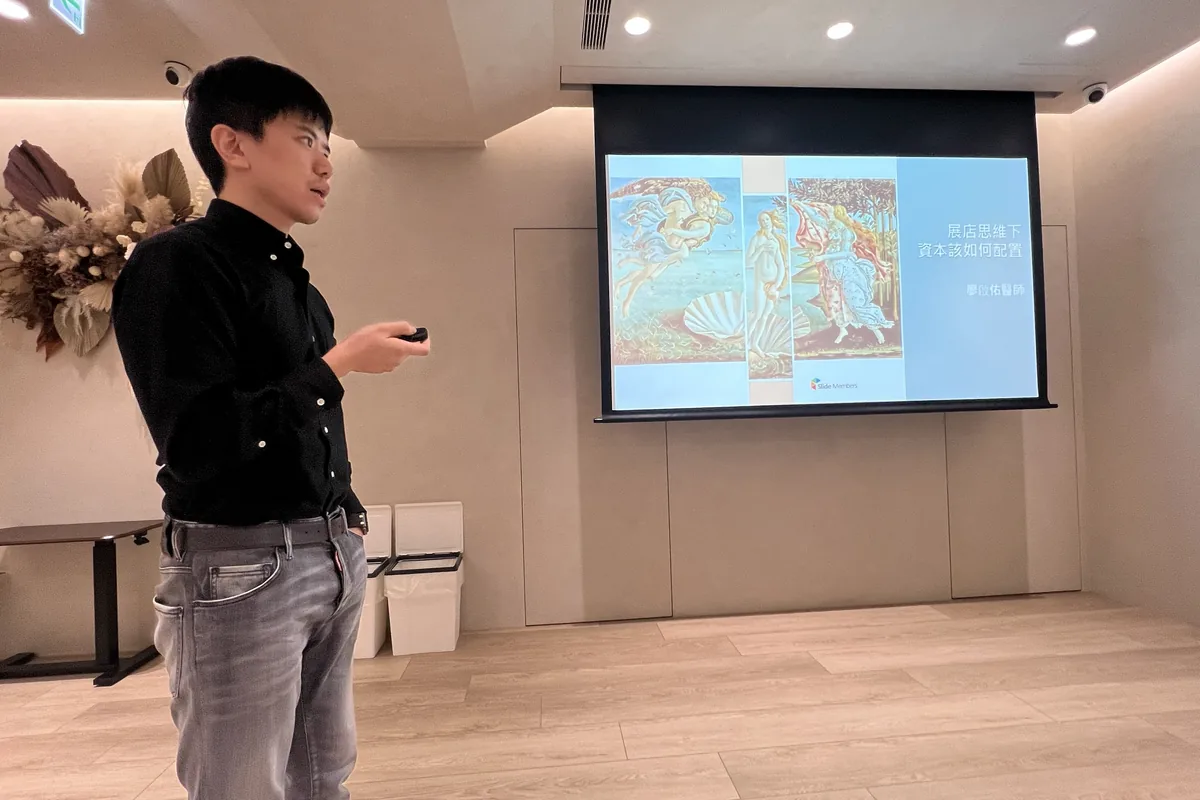 廖醫師站在插畫風「建立堅實的地基・資本流的配置」標題投影片旁分享