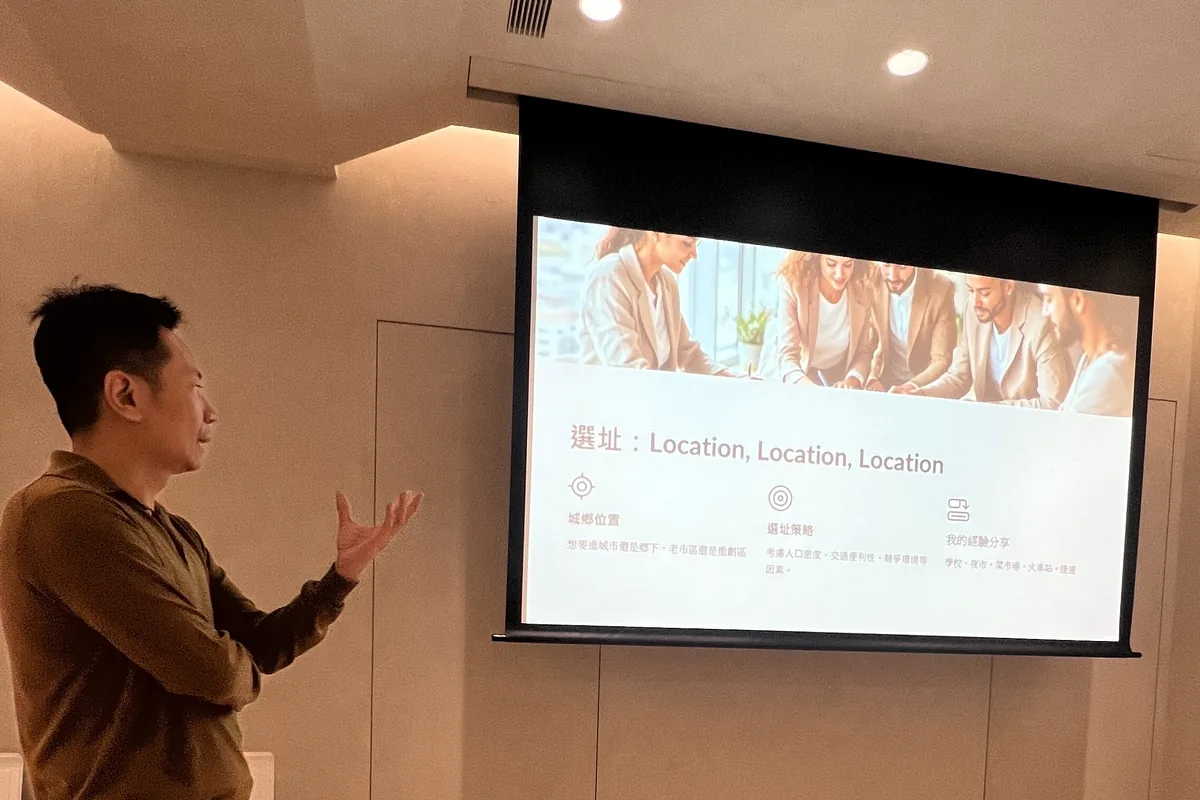 姜國彥醫師站在「選址：Location, Location, Location」投影片旁分享