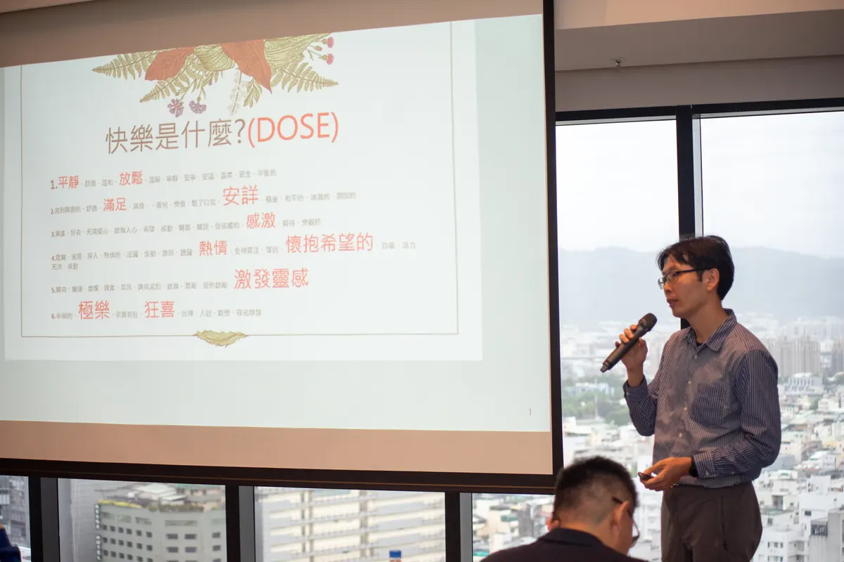 王靖博院長在「快樂是什麼（DOSE）」投影片旁分享