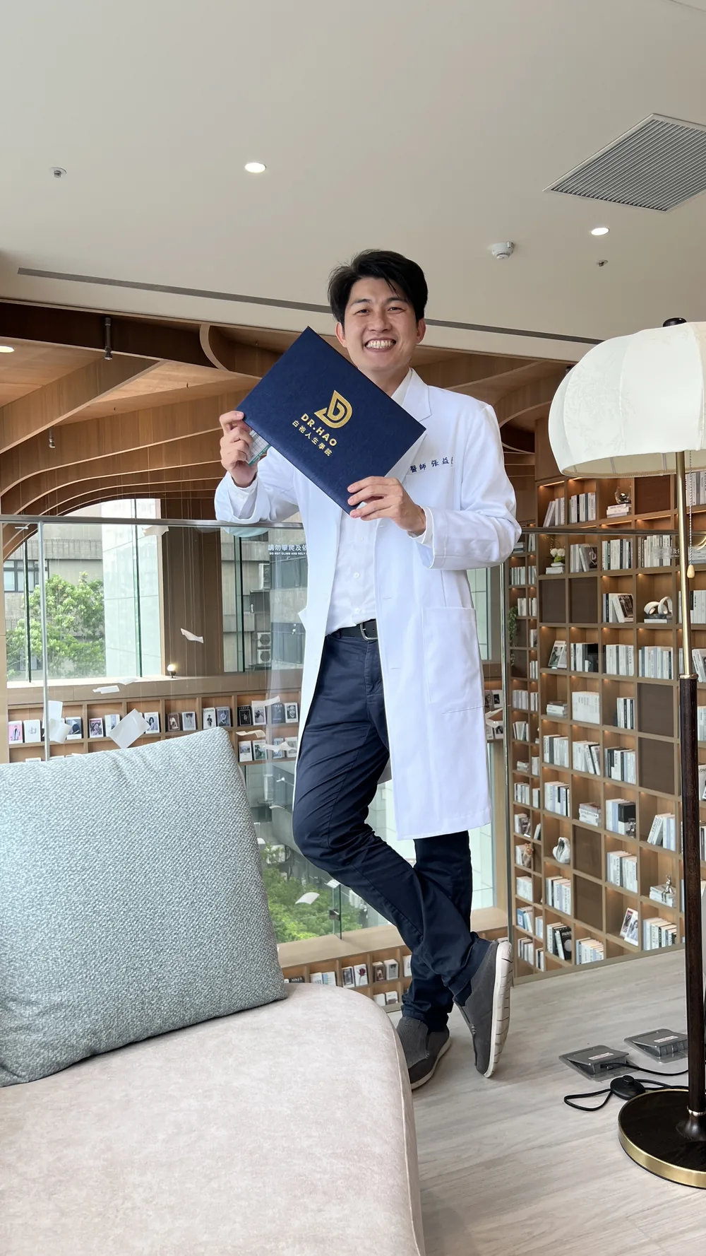一位醫師手持證書在書牆前合影