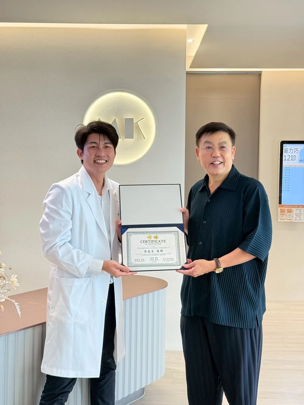 黃福祥執行長在櫃台前頒發參訪證書給張益豪醫師