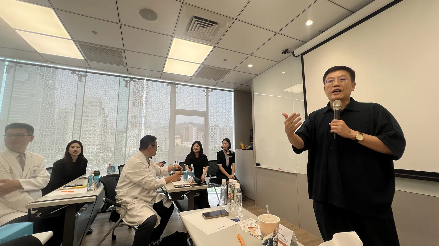 黃福祥執行長站在講堂前手持麥克風分享