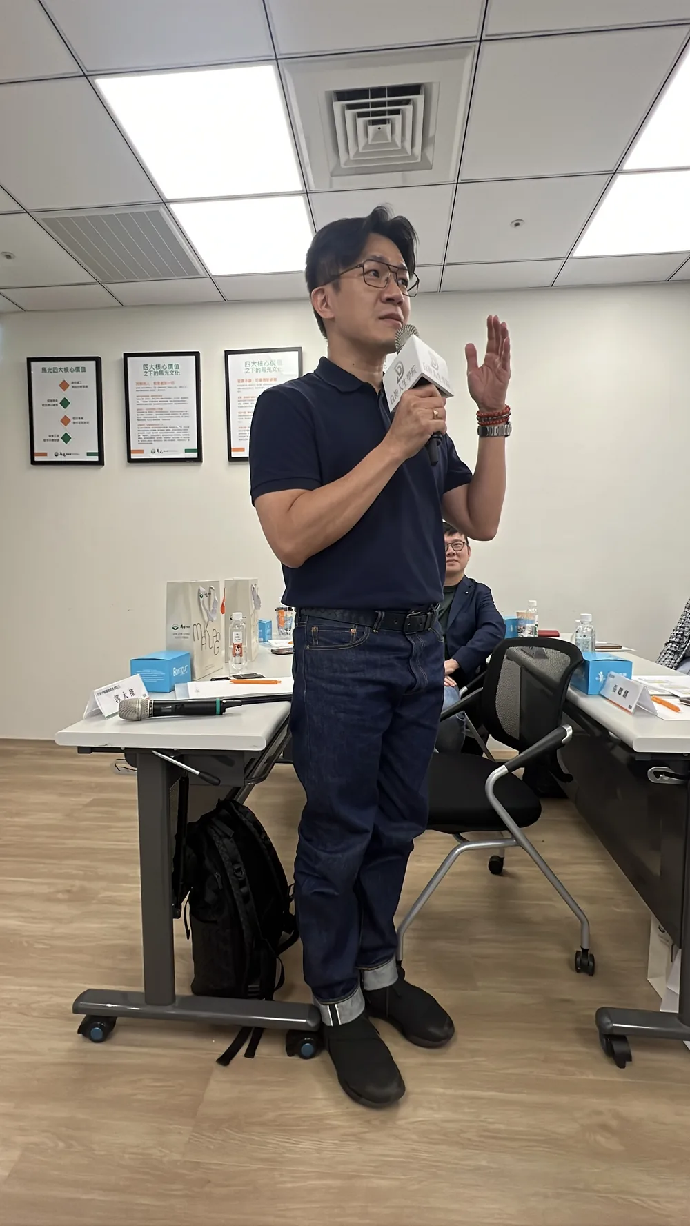 郭大維醫師站著手持麥克風，發表本次參訪心得