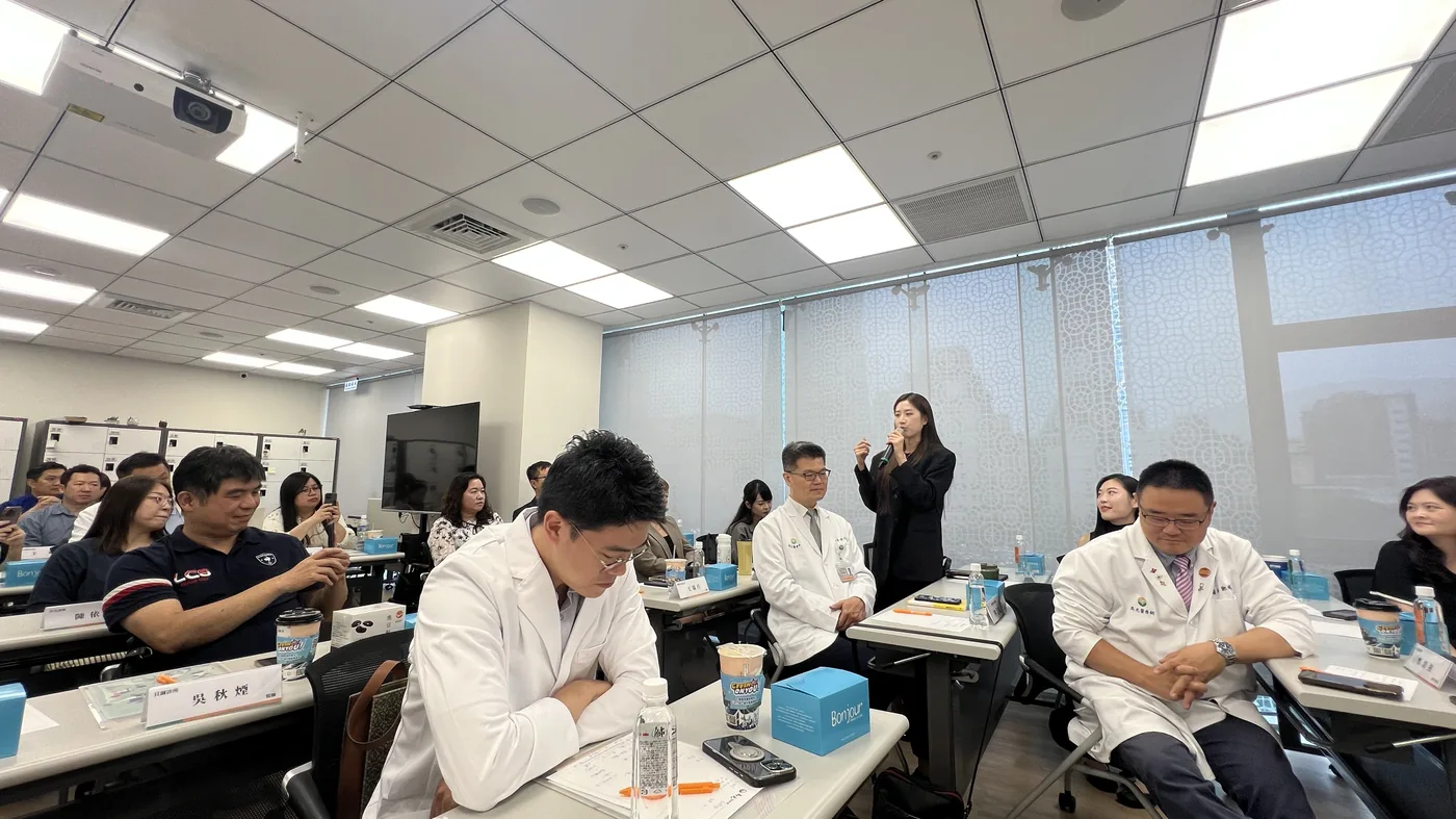講堂內三排長桌坐滿參訪醫師
