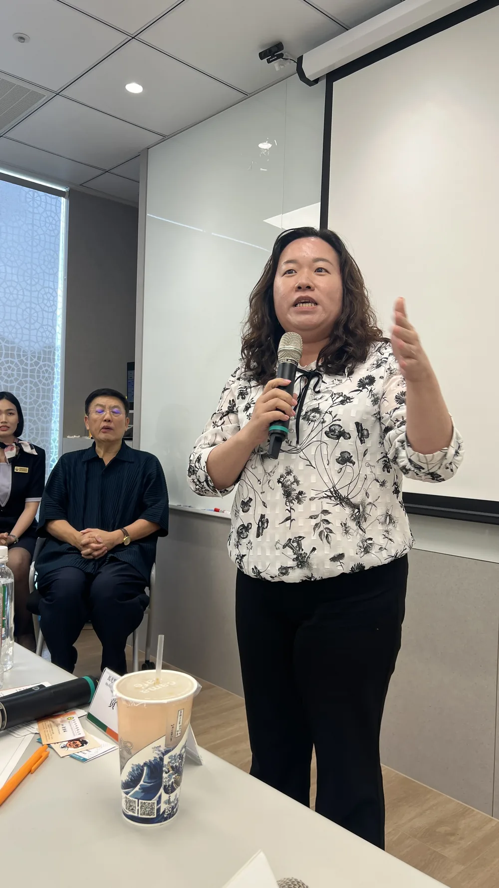 馬光崇學院黃千瑞院長手持麥克風，向參訪醫師分享馬光文化