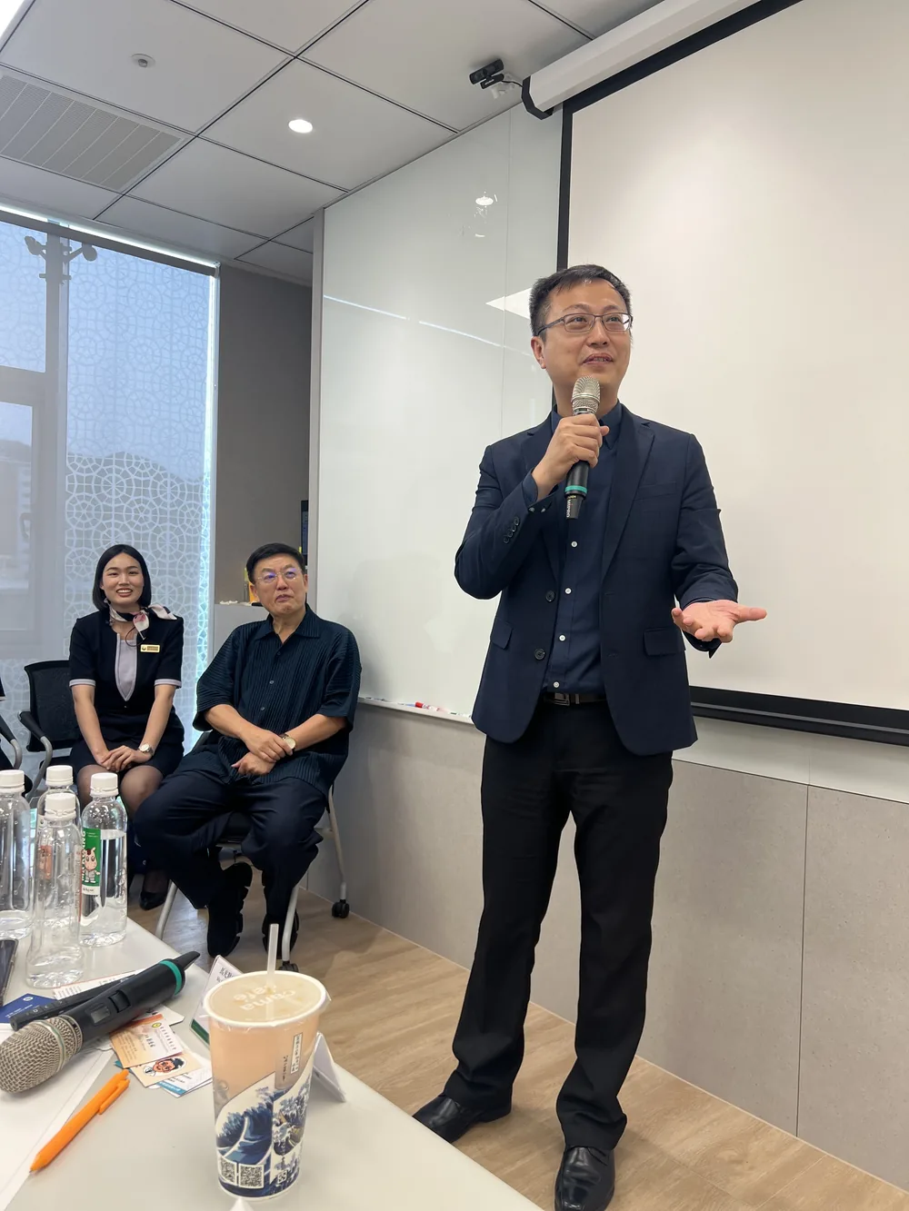 佑昌馬光中醫診所陳昭仁院長手持麥克風，向參訪醫師分享中醫趨勢