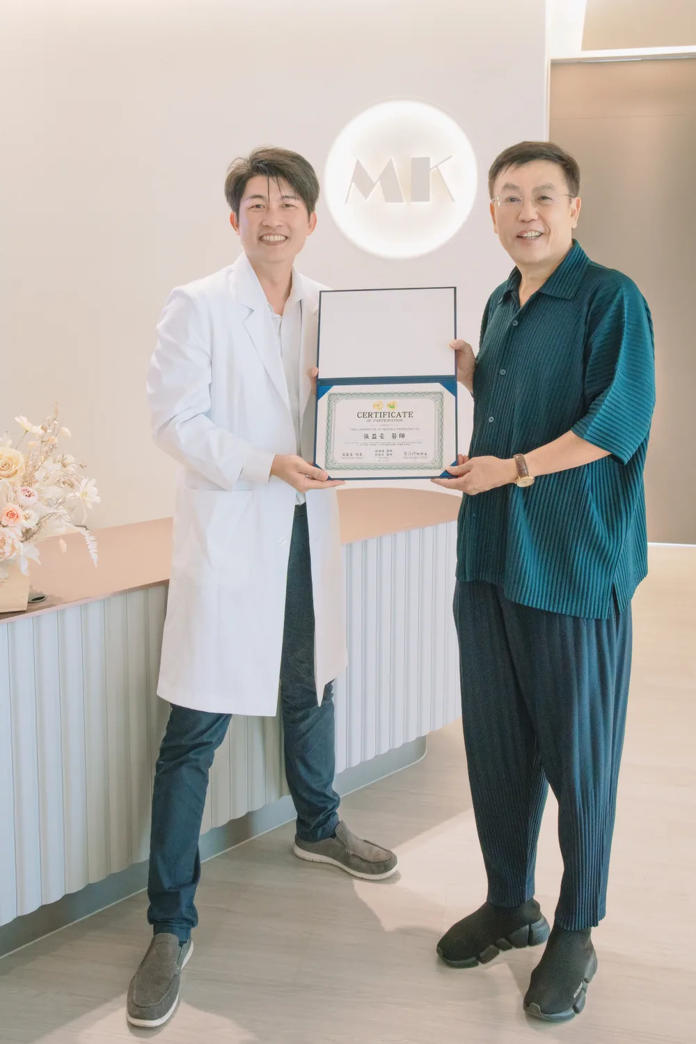 張益豪醫師與黃福祥執行長手持證書在櫃台前合影