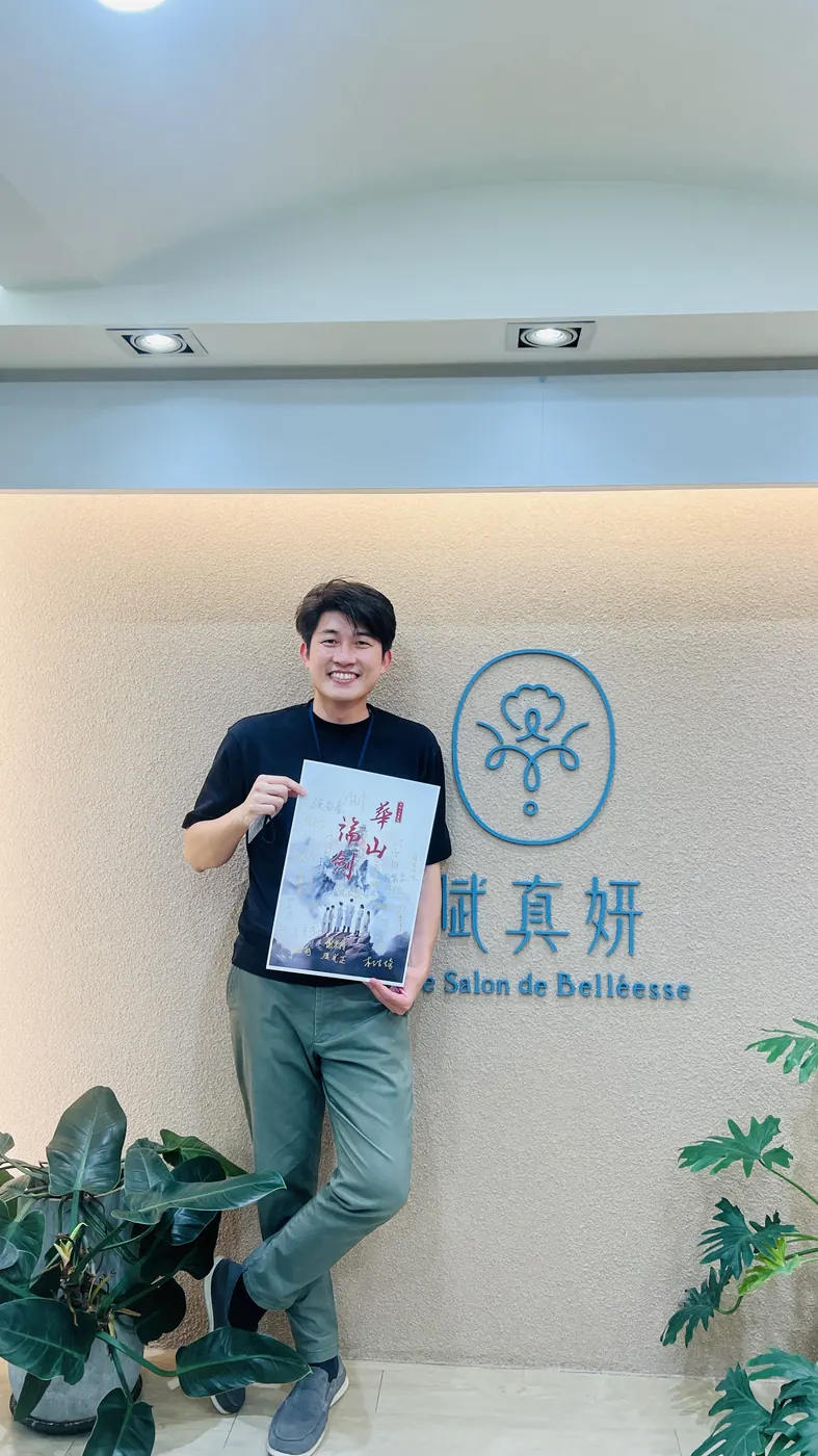 張益豪醫師在賦真妍標誌牆前拿著華山論劍海報