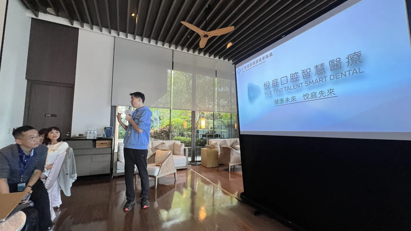 曹皓崴院長手持麥克風站在投影幕旁，投影片寫著悅庭口腔智慧醫療 YUE TING TALENT SMART DENTAL、健康未來 悅庭先來