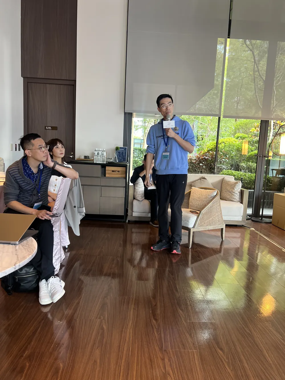 曹皓崴院長手持麥克風站在茶廳前方分享