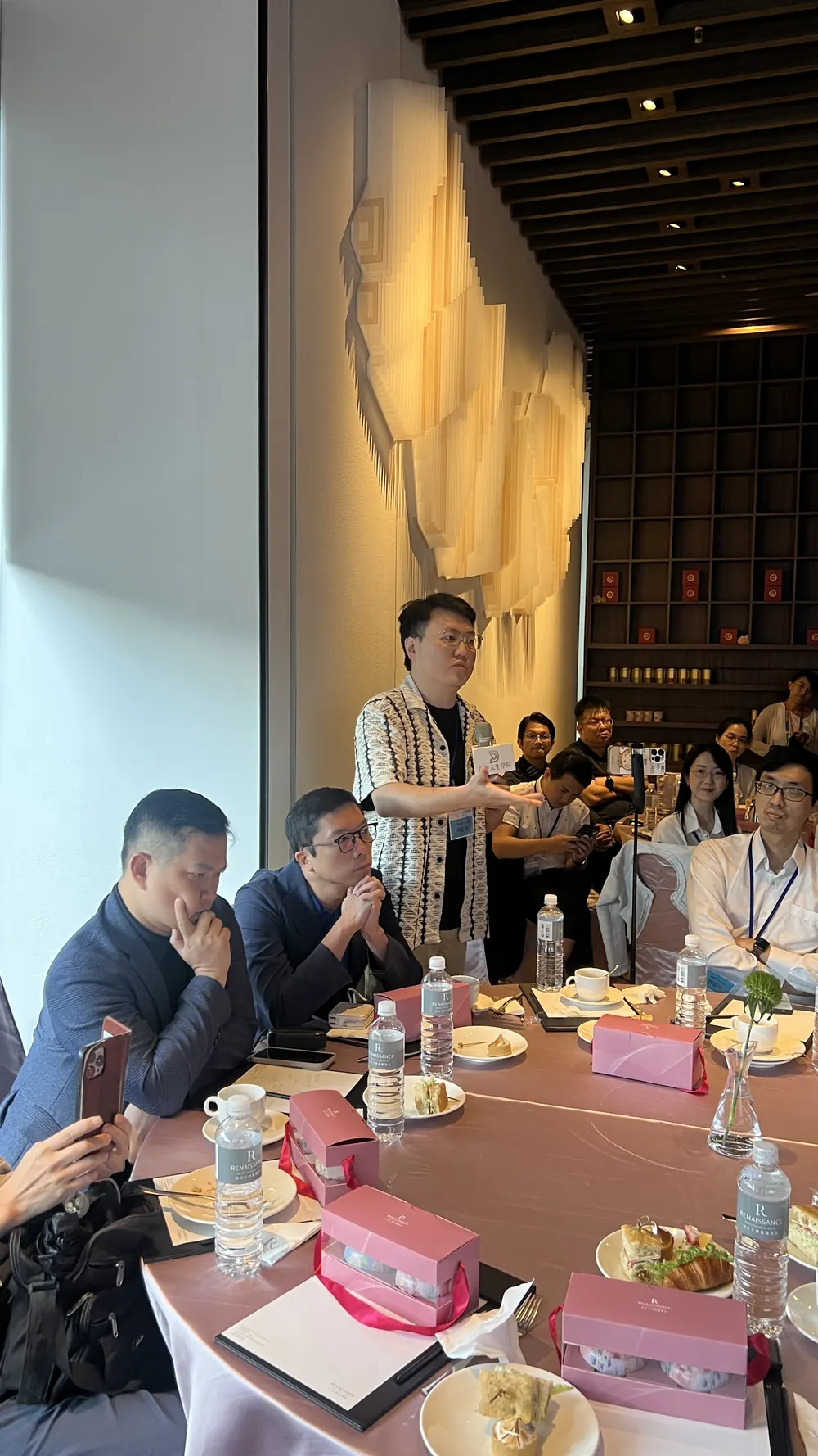 一位參訪醫師在圓桌旁起身，手持麥克風發言