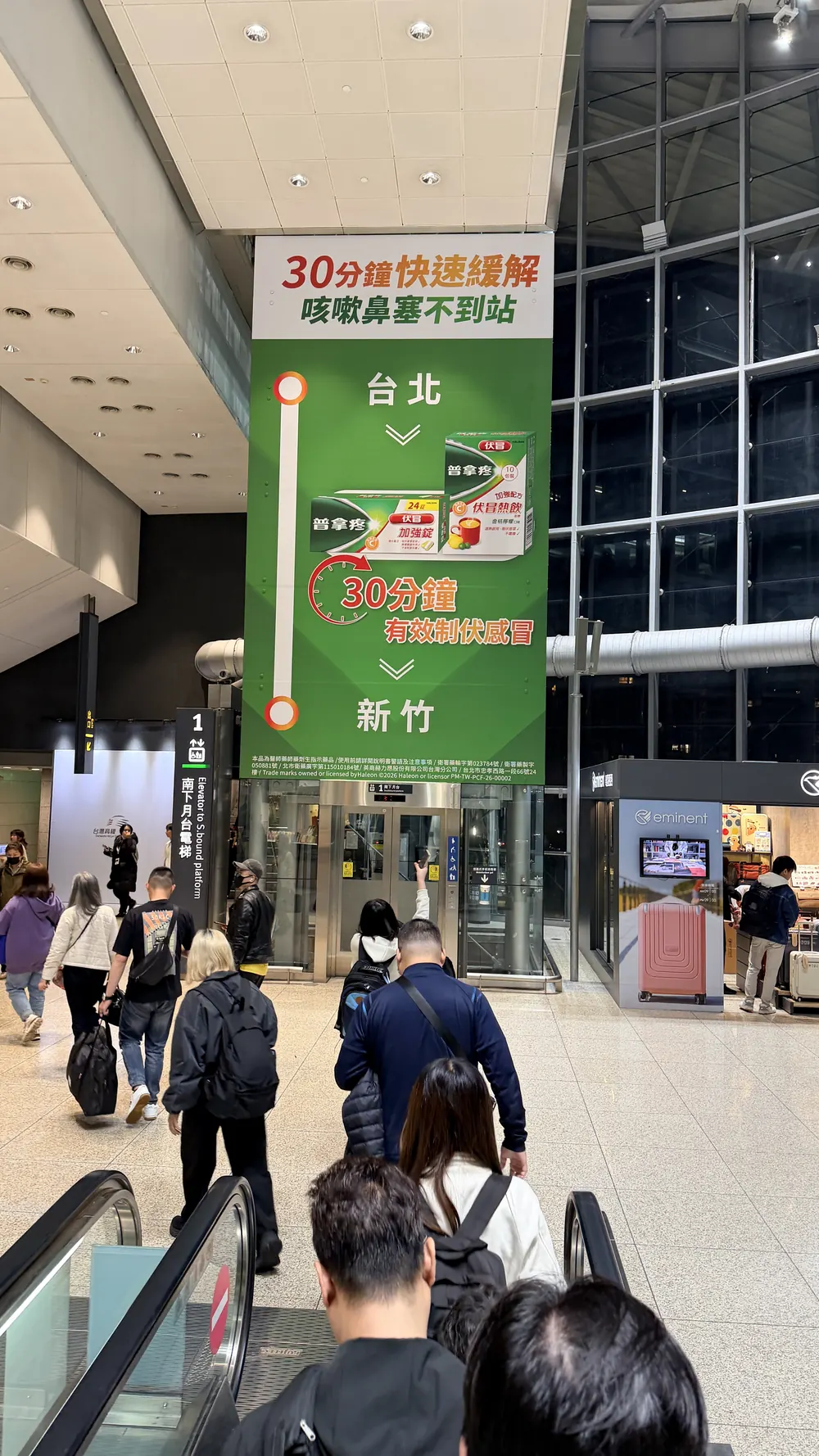 新竹高鐵站大廳懸掛的普拿疼伏冒看板，畫面中央是台北到新竹的路線圖