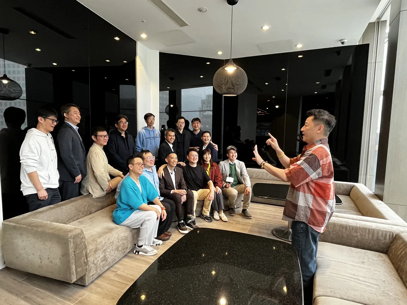 休憩區大合照前，一位與會者站在鏡頭前指揮大家的姿勢