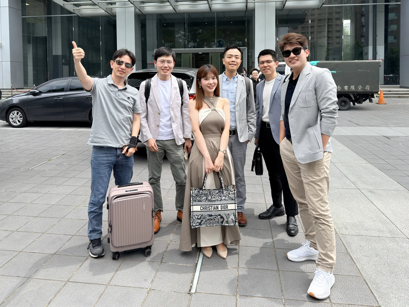 張益豪醫師與五位先到的醫師在民視大樓門口合影，有人還拖著行李箱