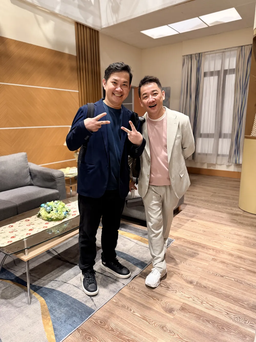 兩位參訪醫師在戲劇棚的客廳佈景裡比手勢合影