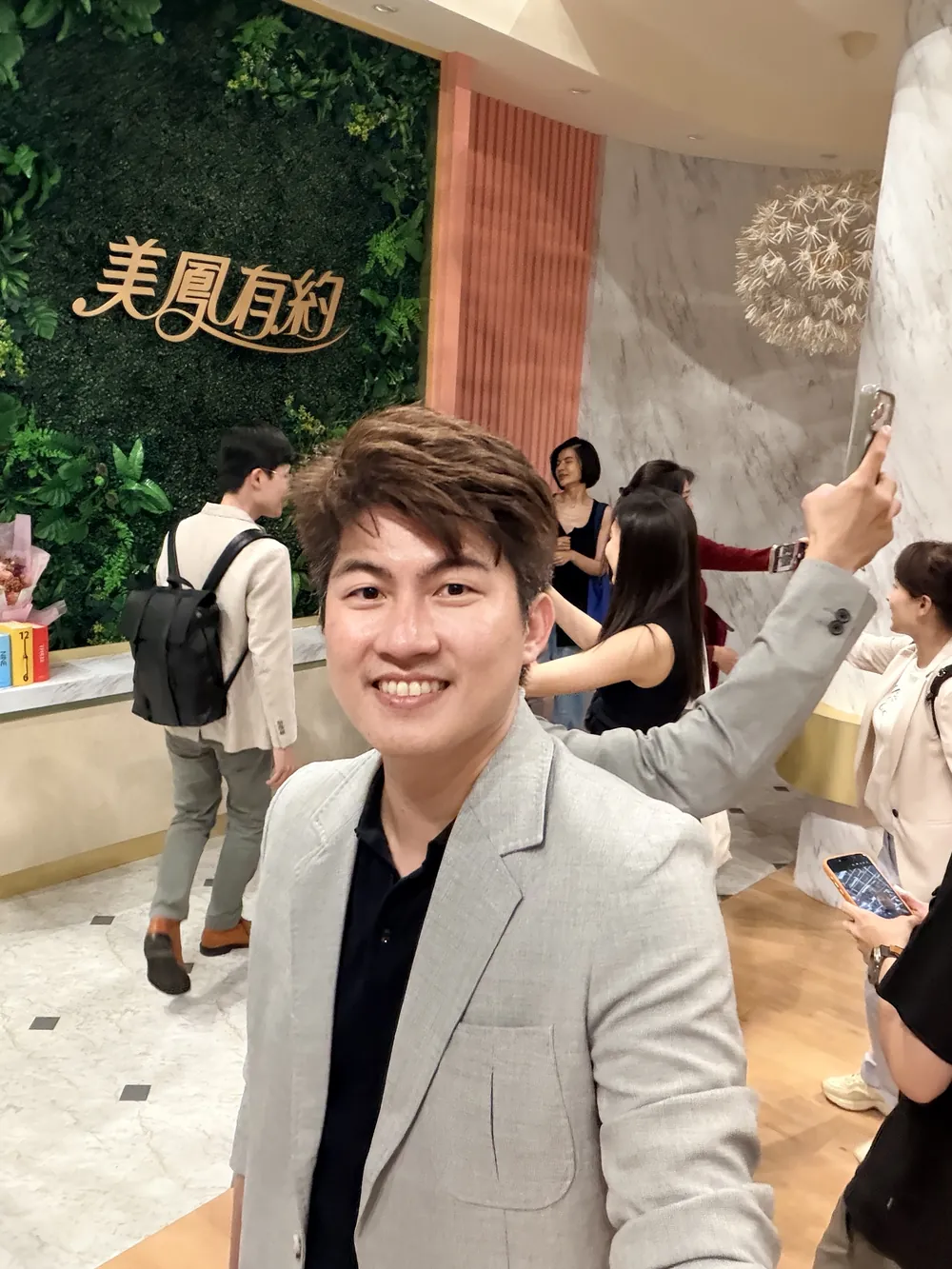 張益豪醫師在《美鳳有約》字樣的植生牆前自拍